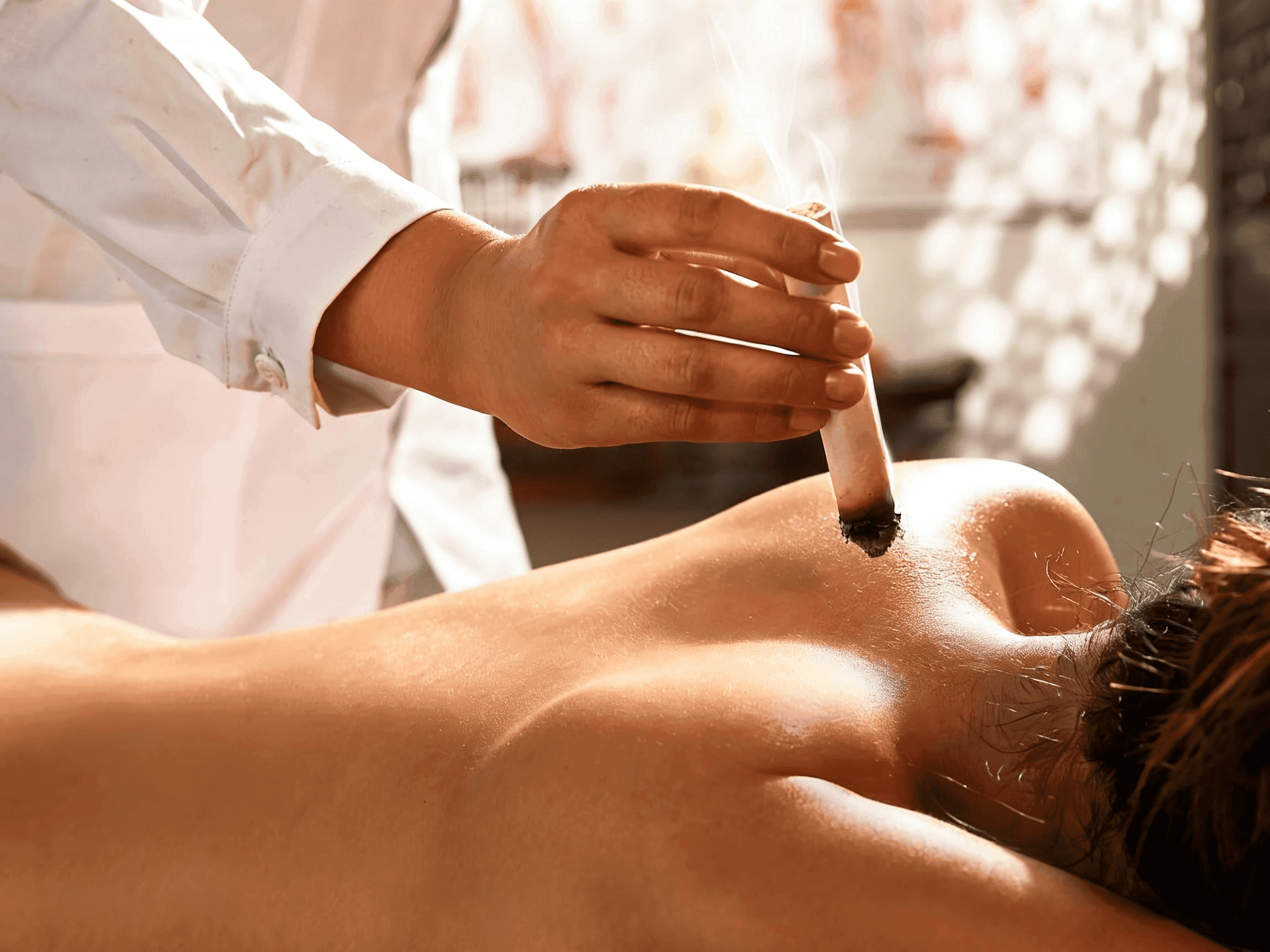 Close-up of fine auricular acupuncture needles placed along the ear in warm sidelight