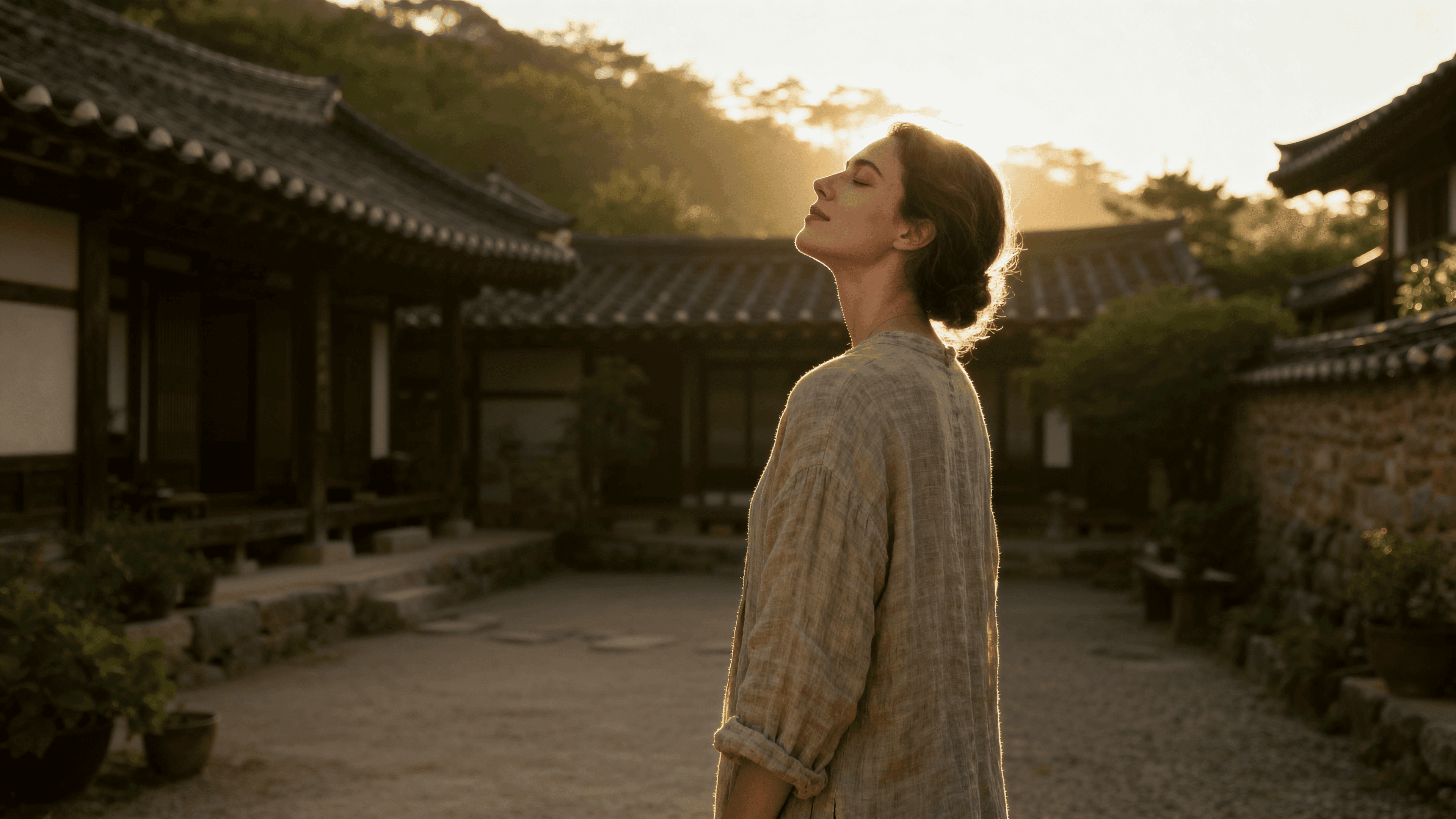 A woman standing quietly in a traditional courtyard garden, morning light across her shoulders, linen clothing, abundant stillness